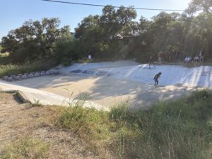 people skateboarding in a big drainage ditch
